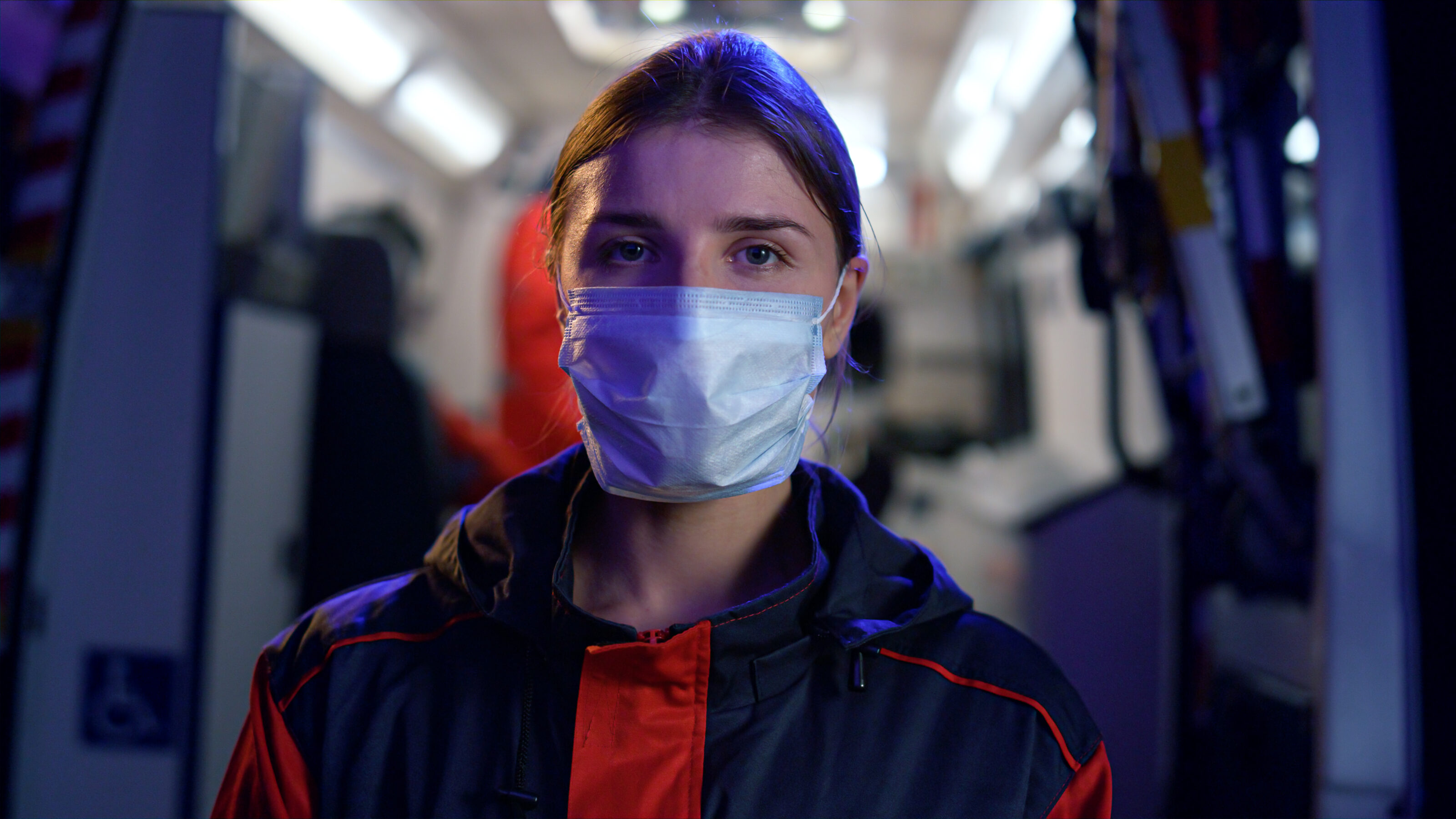 Helferin mit Maske im Porträt vor Krankenwagen