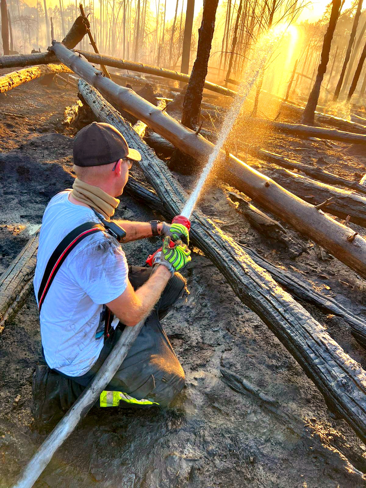 Peter Groh von der Freiwilligen Feuerwehr Münster, mit einem Feuerwehrschlauch im Wald