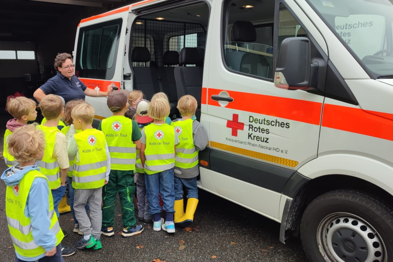 Eine Gruppe Kinder steht vor einem Rettungswagen des Deutschen Roten Kreuzes