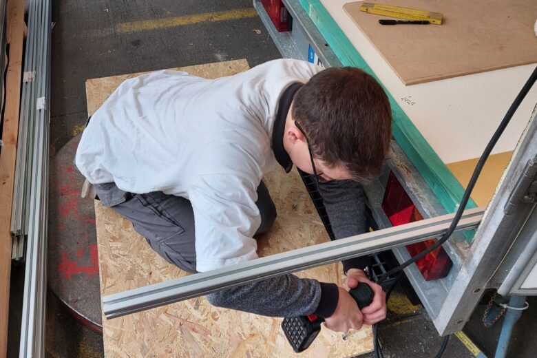 Man sieht einen Ehrenamtlichen, der eine handwerkliche Arbeit am Anhänger durchführt