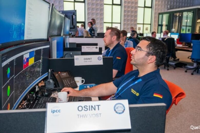 Auf dem Foto sieht man im Vordergrund zwei Einsatzkräfte des Virtual Operations Support Team, die vor großen Bildschirmen mit Computern arbeiten.