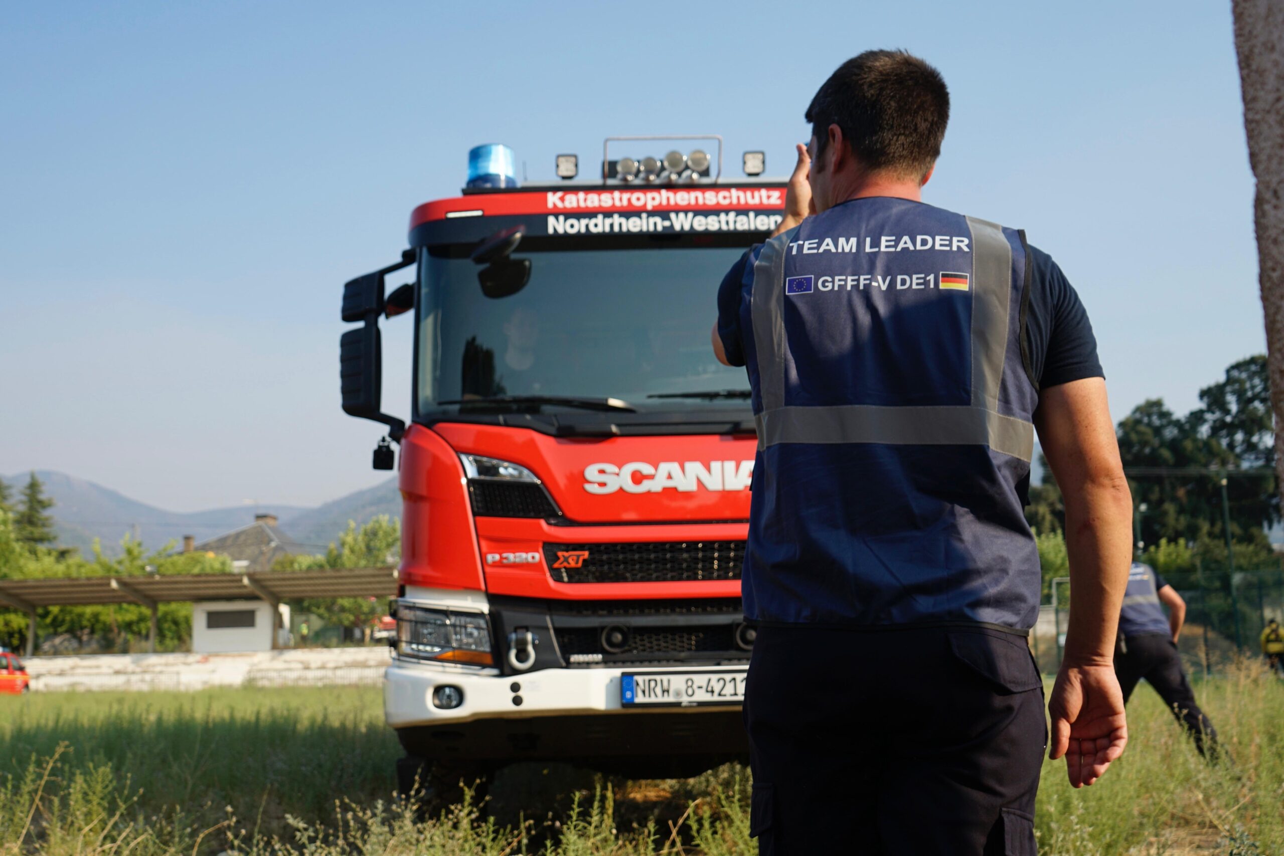 Der Team Leader des Waldbrandmoduls steht vor einem Feuerwehrauto mit der Schrift: Katastrophenschutz Nordrhein-Westfalen